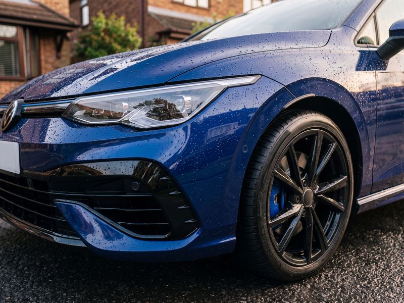 Freshly hand-washed dark blue hatchback with water beading on glossy paintwork